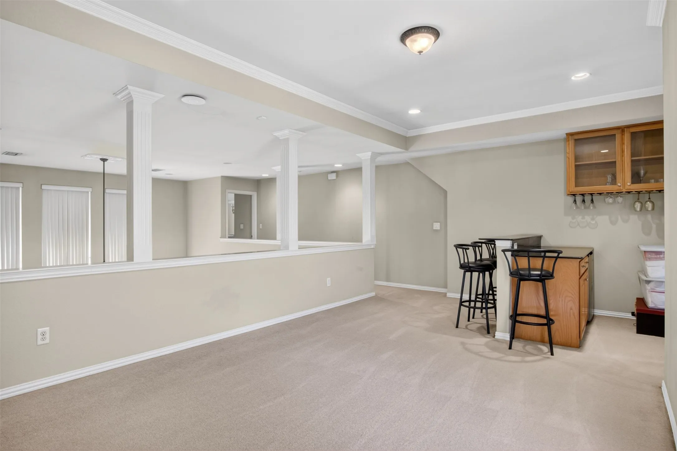 Open loft space featuring plush carpeting, a built-in wet bar with wood cabinetry, and recessed lighting