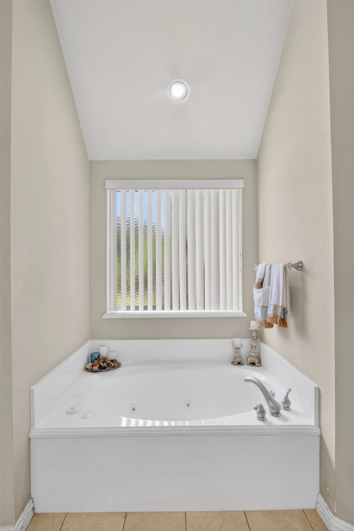 Recessed jetted bathtub with a tile surround and chrome fixtures