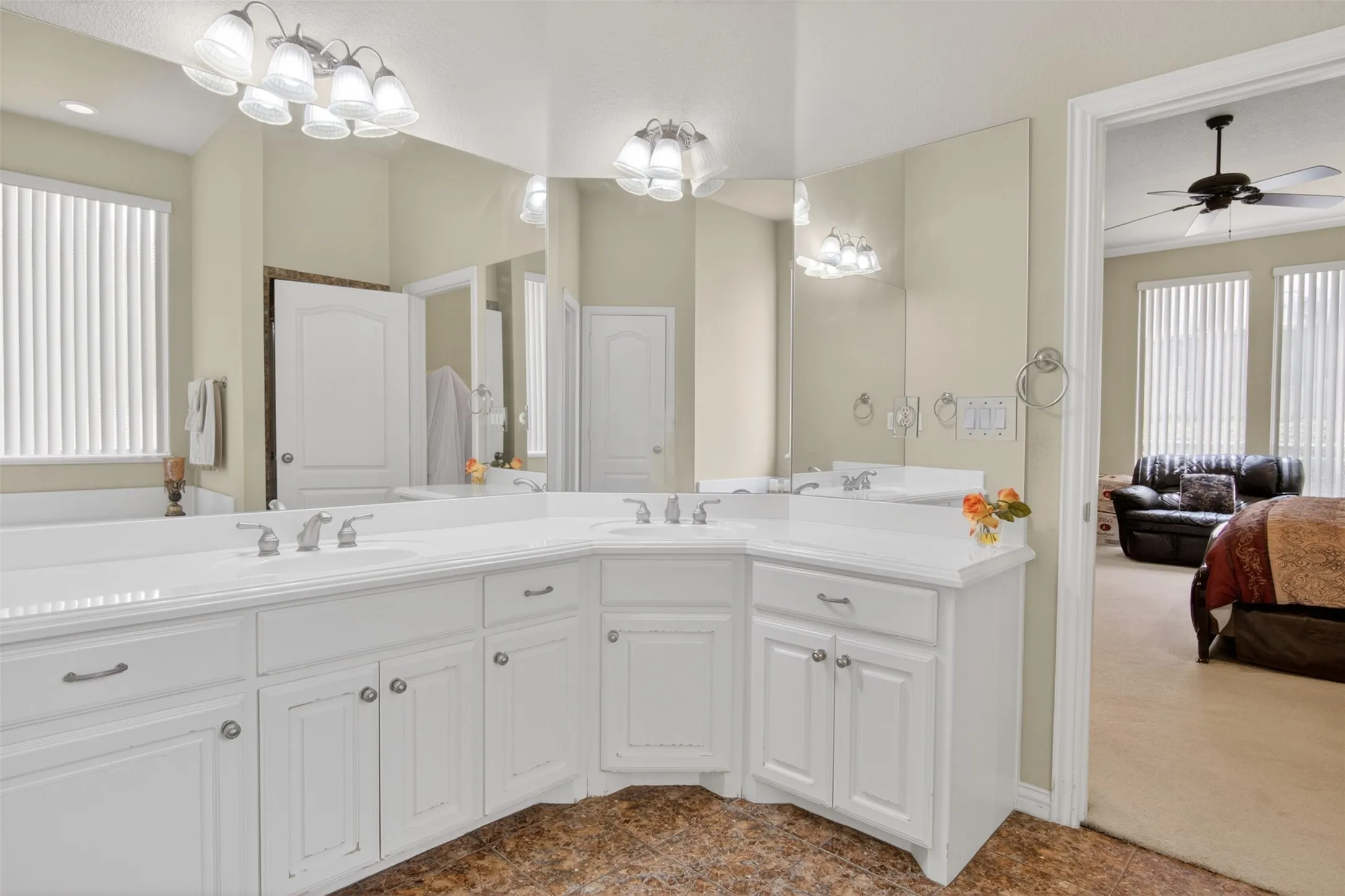Spacious vanity featuring dual sinks, white cabinetry, integrated countertop, and large wall-mounted mirrors