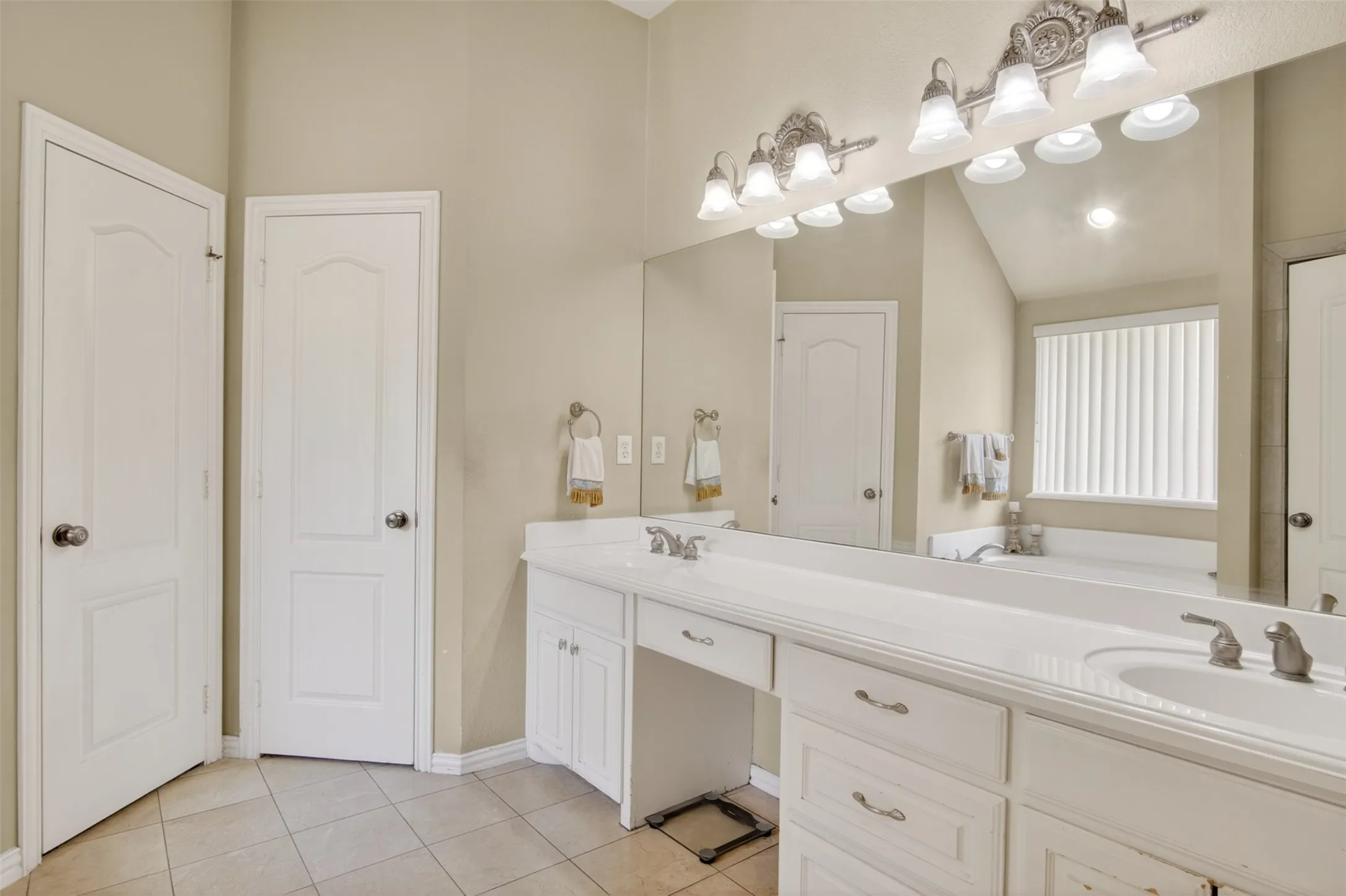 Bathroom featuring a dual vanity with integrated sinks, extensive countertop space, and white cabinetry