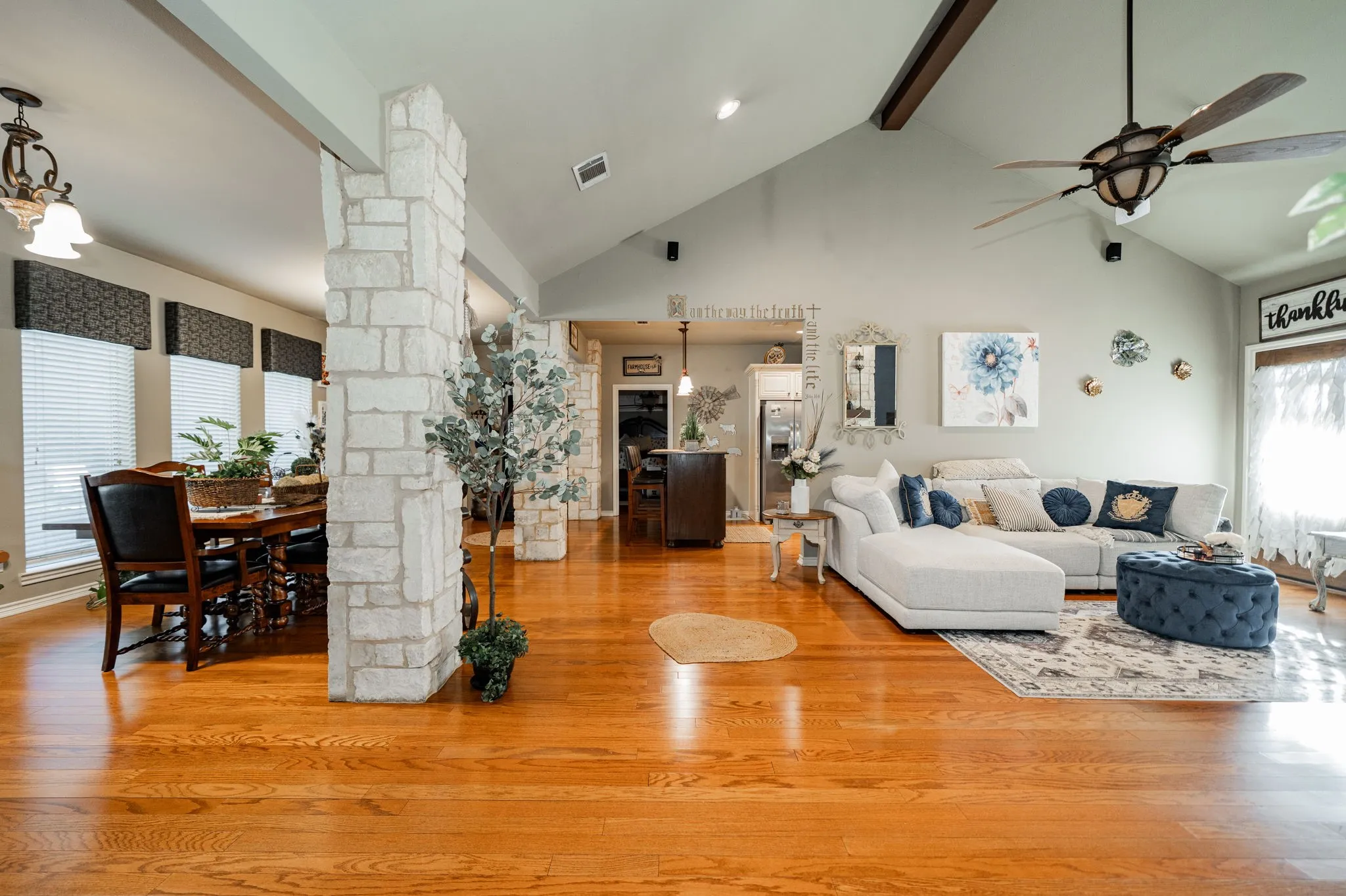 Expansive living area featuring wood-finish flooring, vaulted ceilings, and a decorative ceiling fan