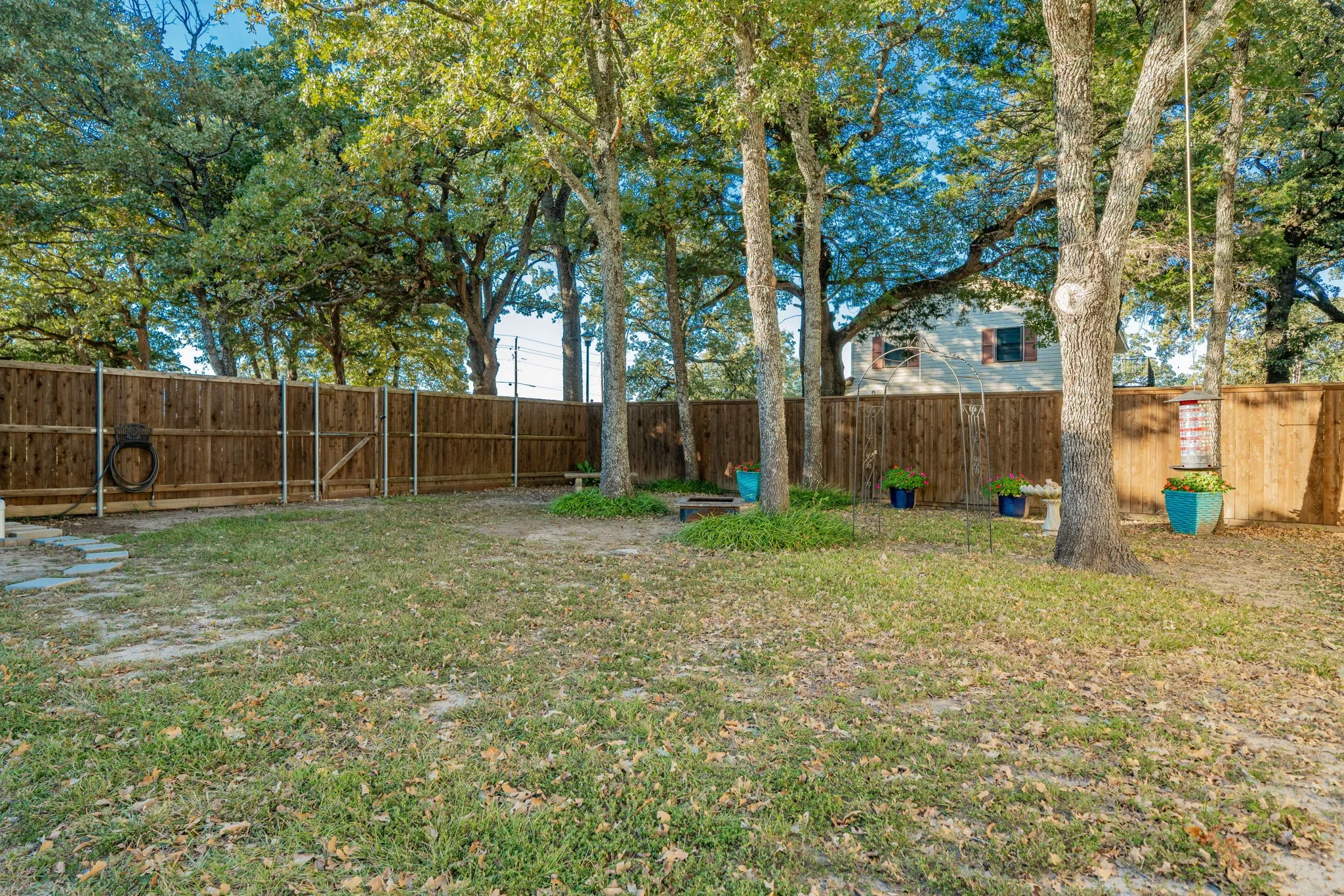Fenced backyard featuring mature trees, a wooden privacy fence, and a gate