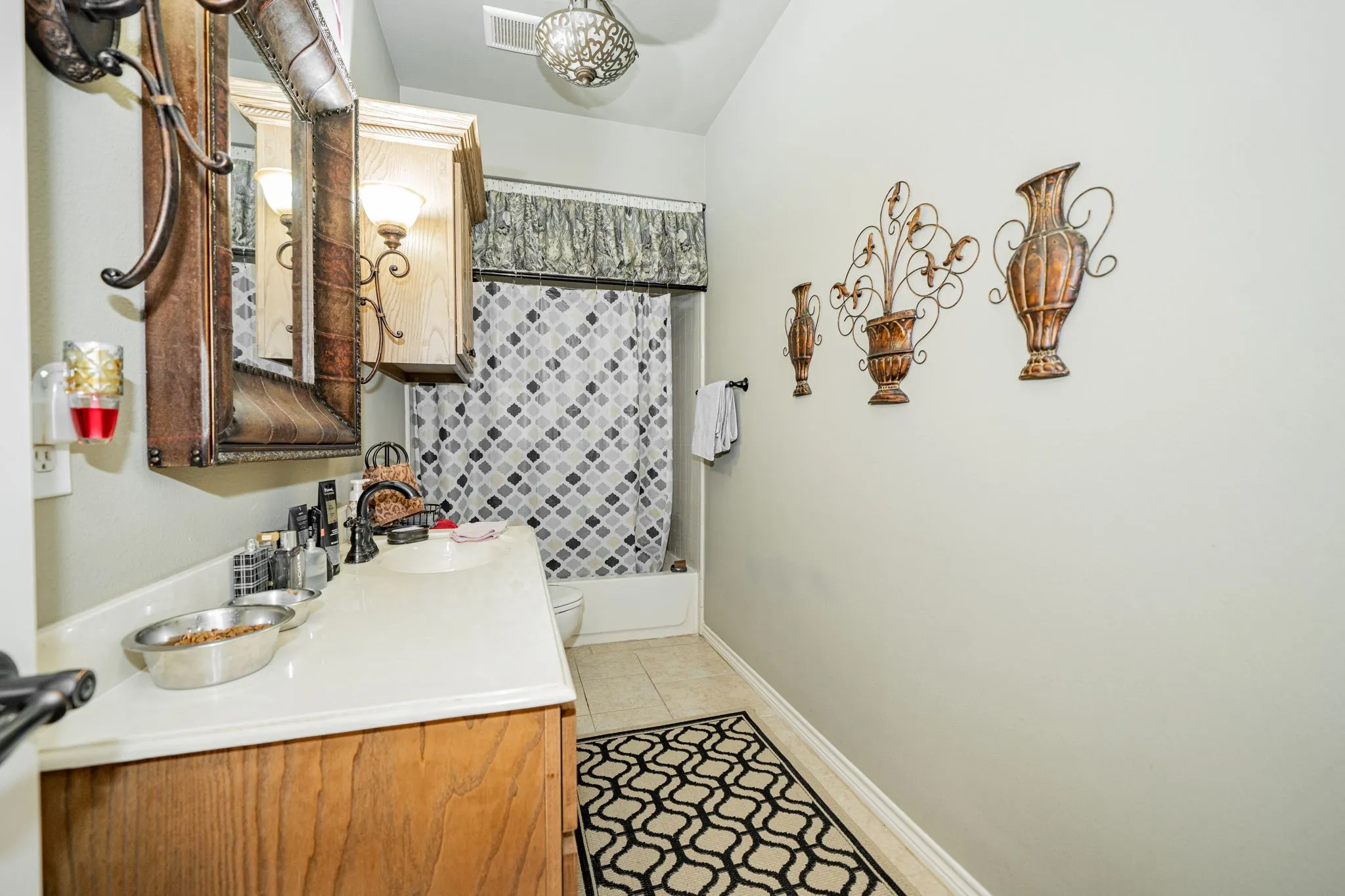 Bathroom vanity with a light-toned countertop, wood-finish cabinetry, and a single basin sink