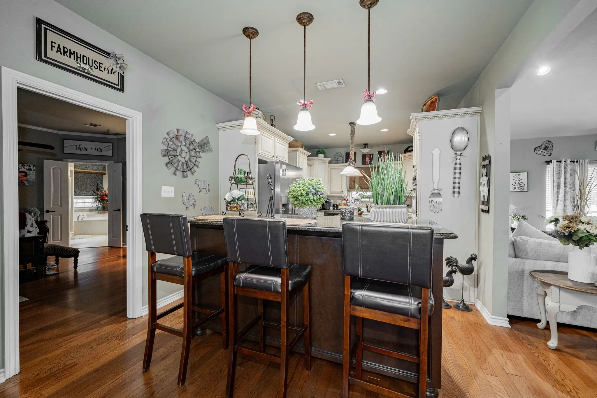 Kitchen island with a dark wood-finish base, dark countertop, and three pendant lights