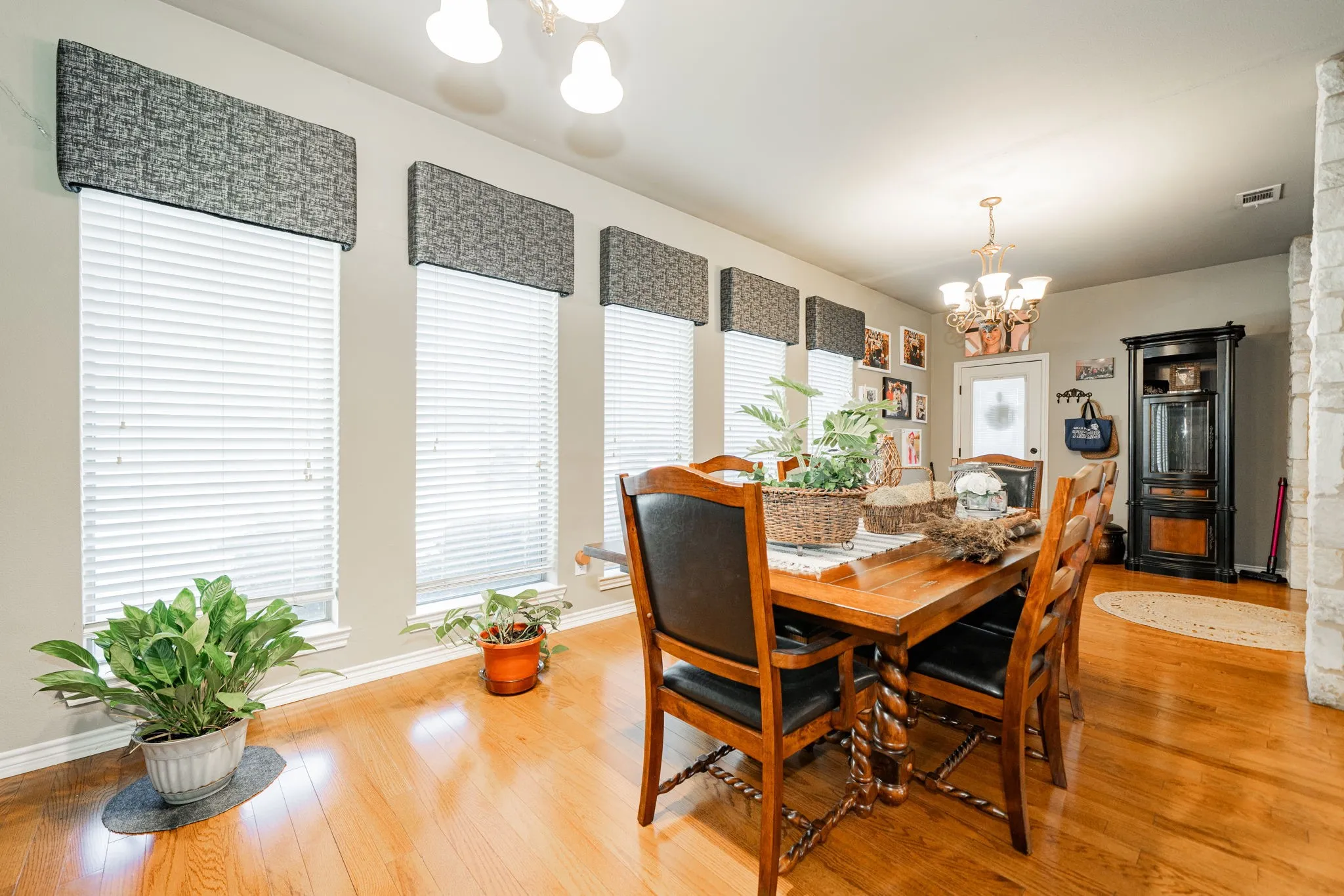 Dining area featuring wood-finish flooring and multiple windows with blinds and valances