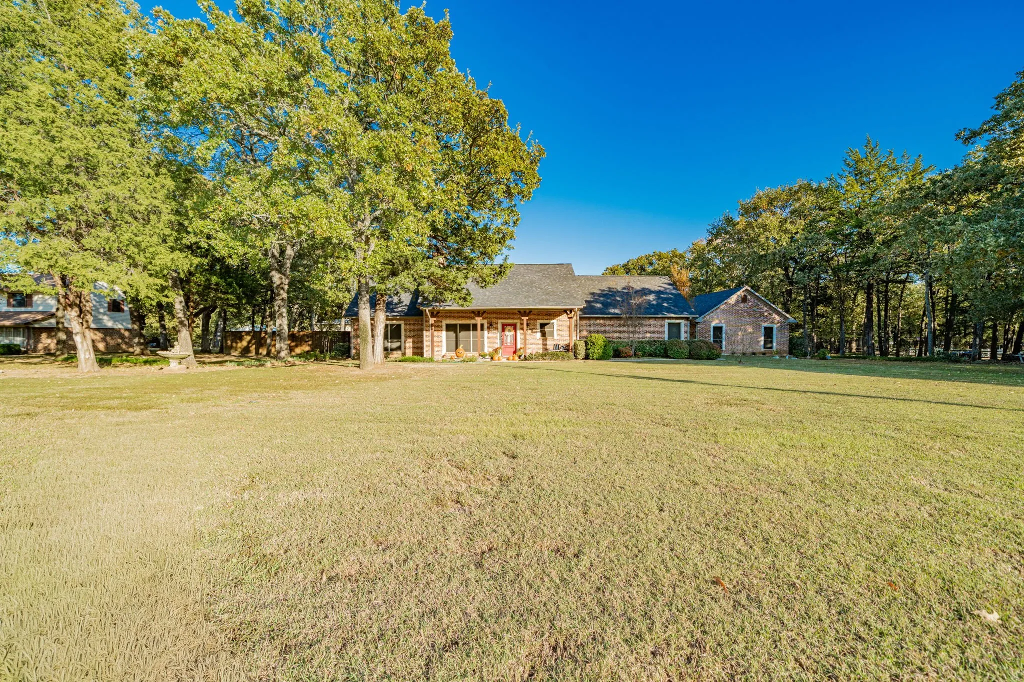 Expansive front lawn with mature trees providing partial shade