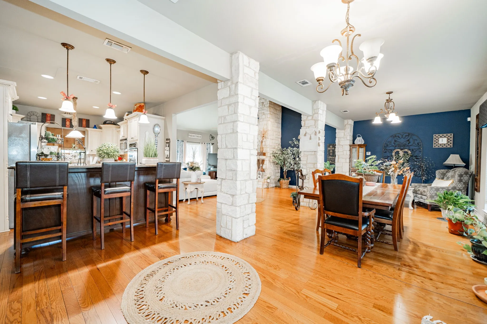 Spacious interior featuring wood-finish flooring, stone-clad pillars, and a ceiling-mounted chandelier