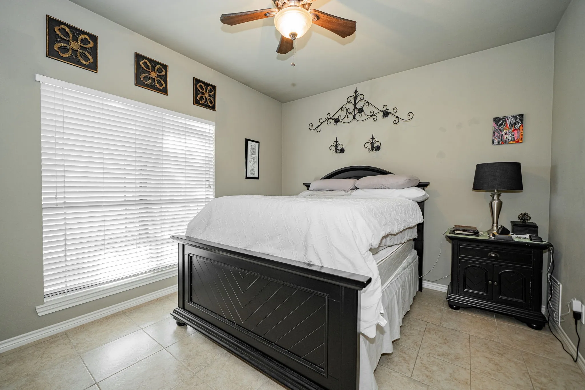 Room featuring light-toned tile flooring, neutral wall paint, and a large window with horizontal blinds