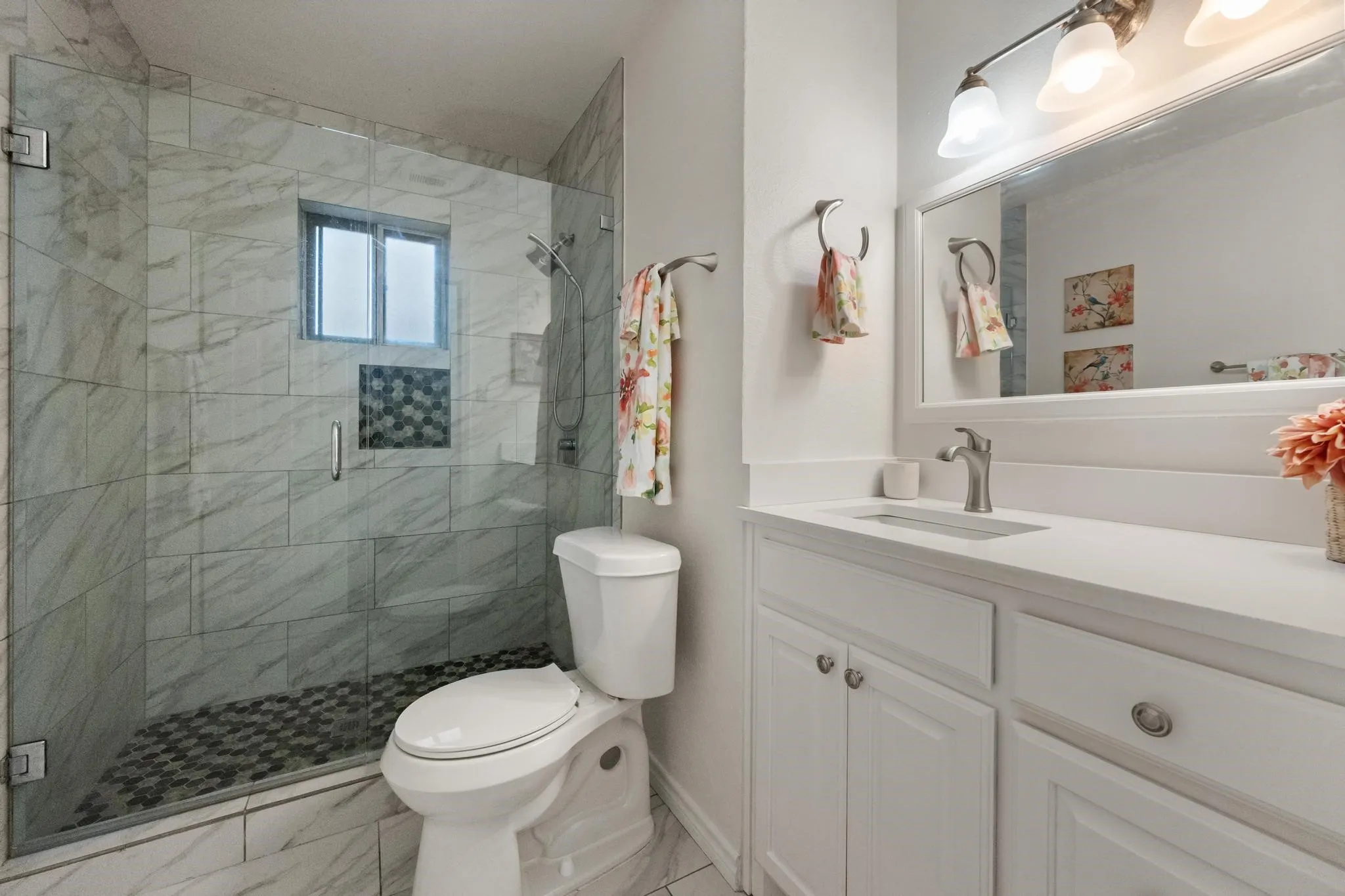 Updated fixtures and finishes transform this bathroom into a serene retreat, complete with stylish tile work and ample storage.