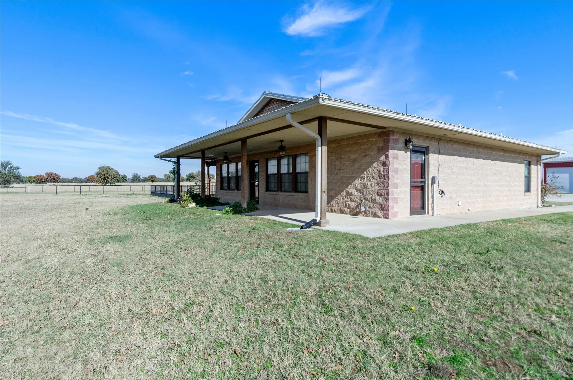 Rear view of house with covered porch, a ceiling fan, and concrete block siding