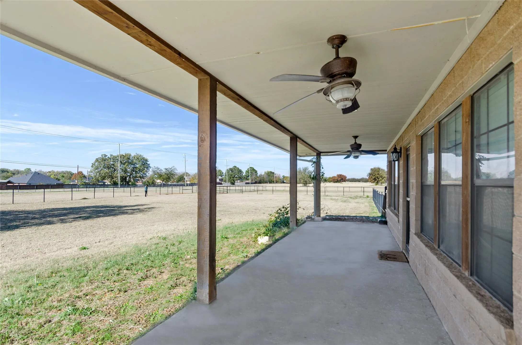 Fenced backyard featuring ceiling fan, a view of countryside, and a patio