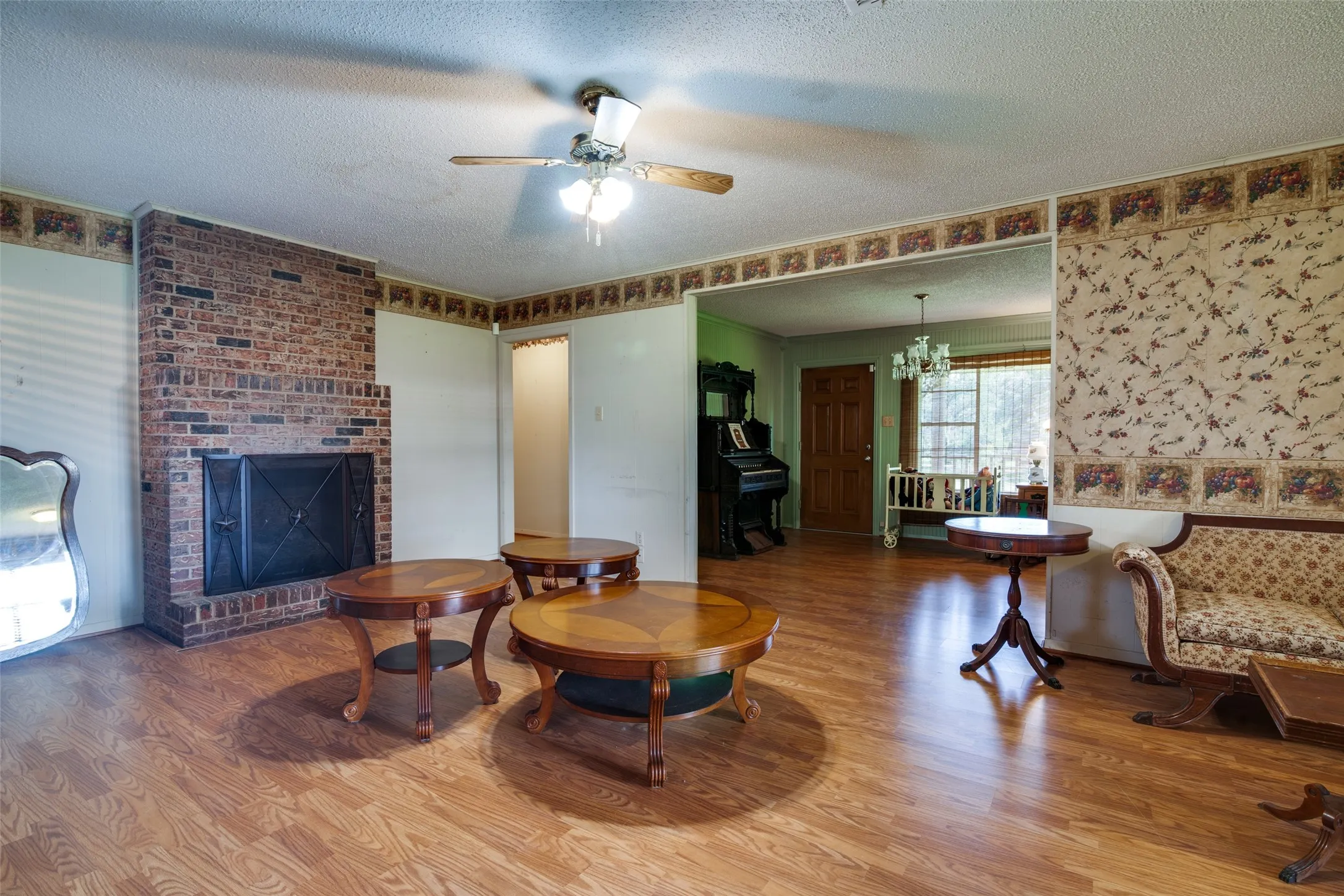 Spacious interior featuring wood-finish flooring and a brick fireplace with a metal screen