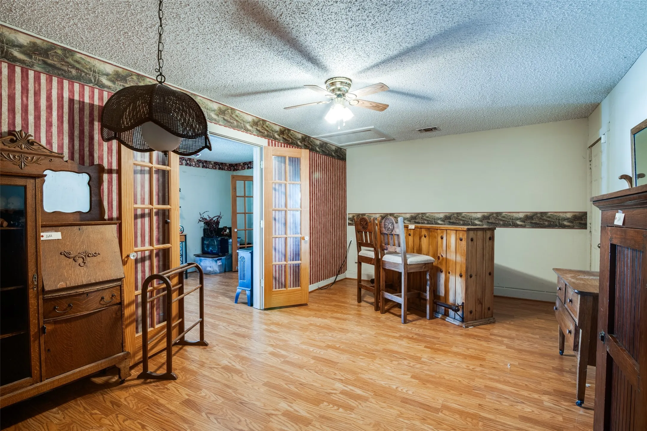 Spacious room featuring wood-finish flooring, a ceiling fan, and French doors