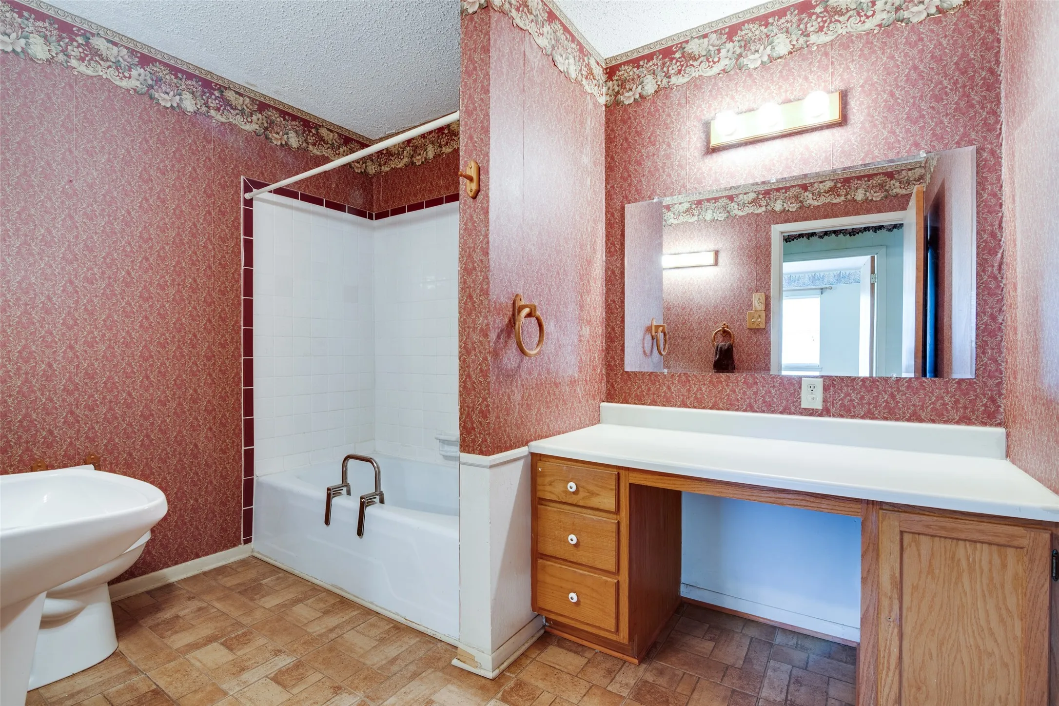 Bathroom featuring a combination bathtub and shower, a built-in vanity with wood-finish cabinetry, a large mirror, and tiled flooring