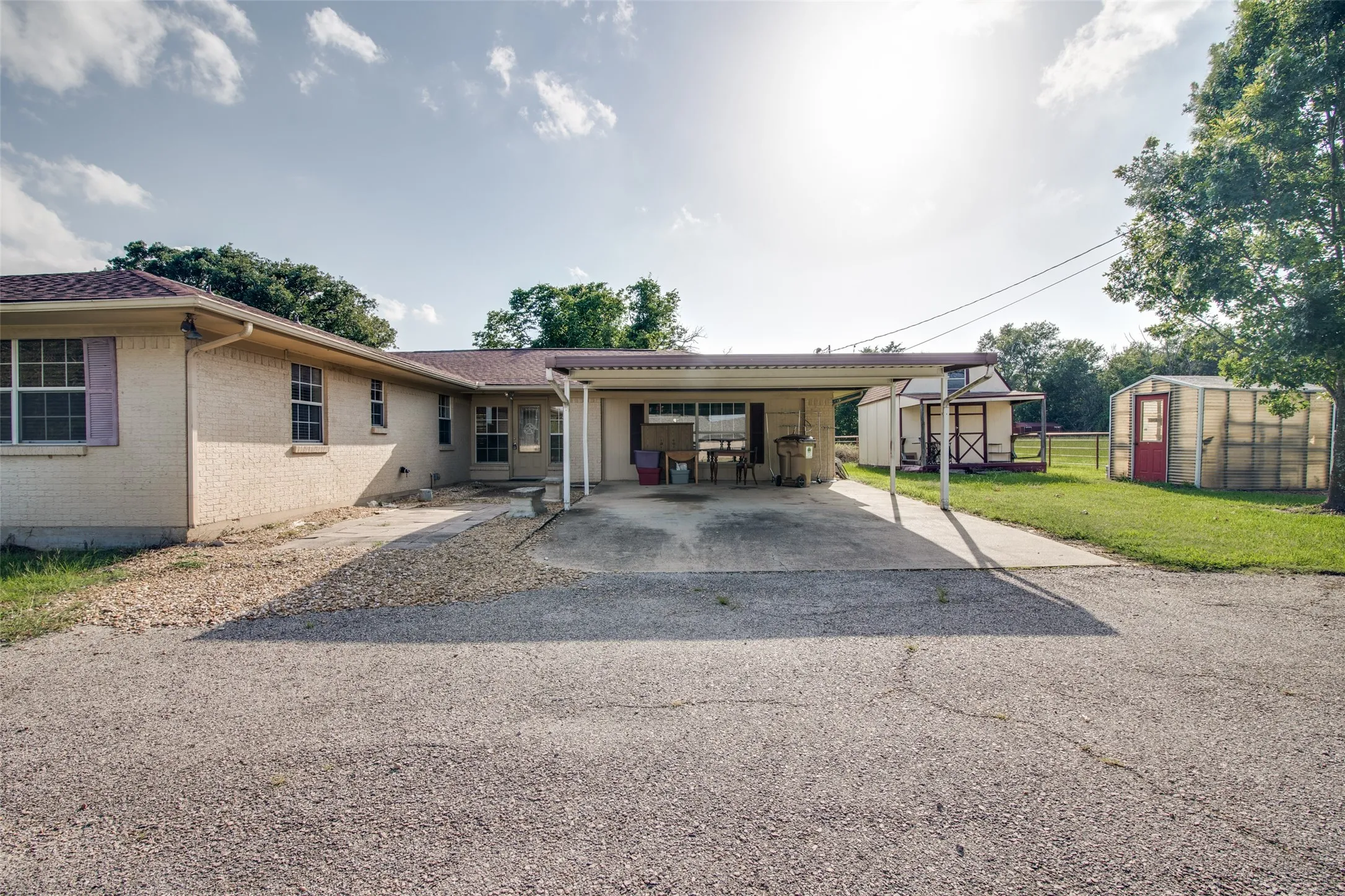 Exterior featuring a carport, light brick siding, and a contrasting roofline