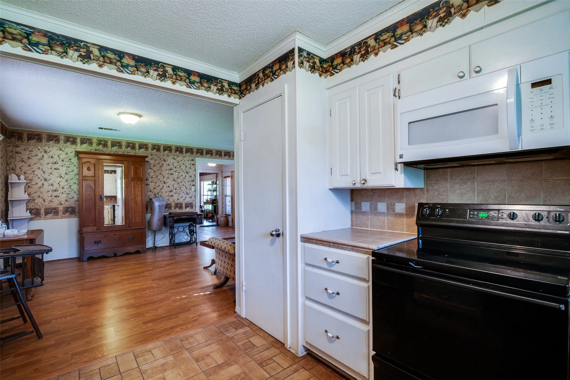 Kitchen area featuring white cabinetry, a built-in microwave, and a black electric range