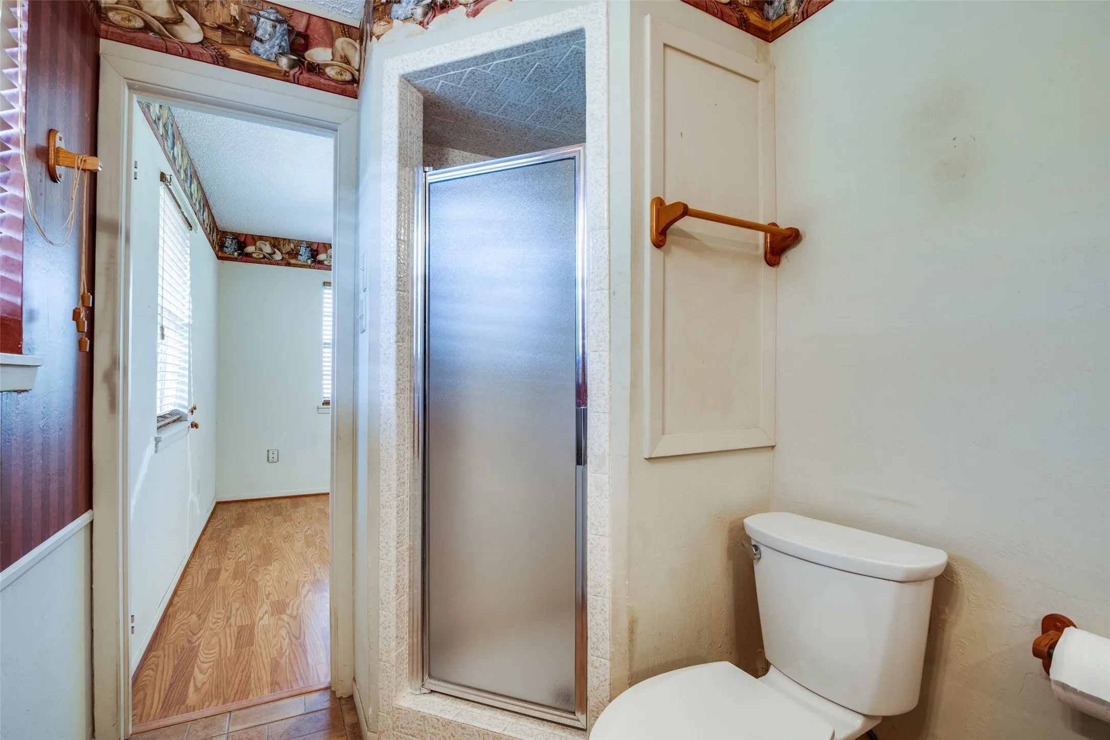 Three-piece bathroom featuring a walk-in shower with a frosted glass door, a toilet, and built-in wall cabinetry