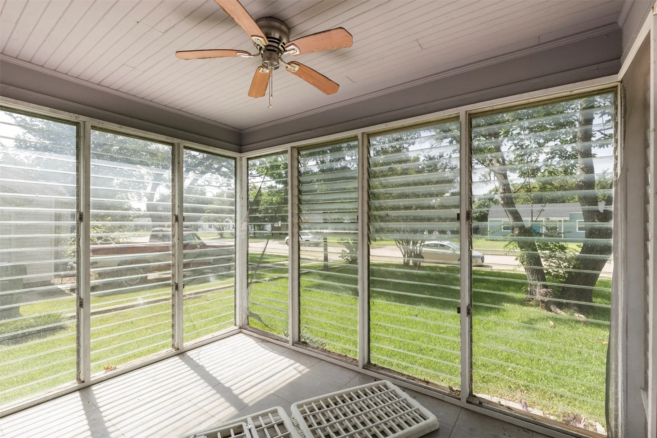 Enclosed porch featuring jalousie windows, a wood-finish ceiling fan, tongue-and-groove ceiling, and concrete flooring