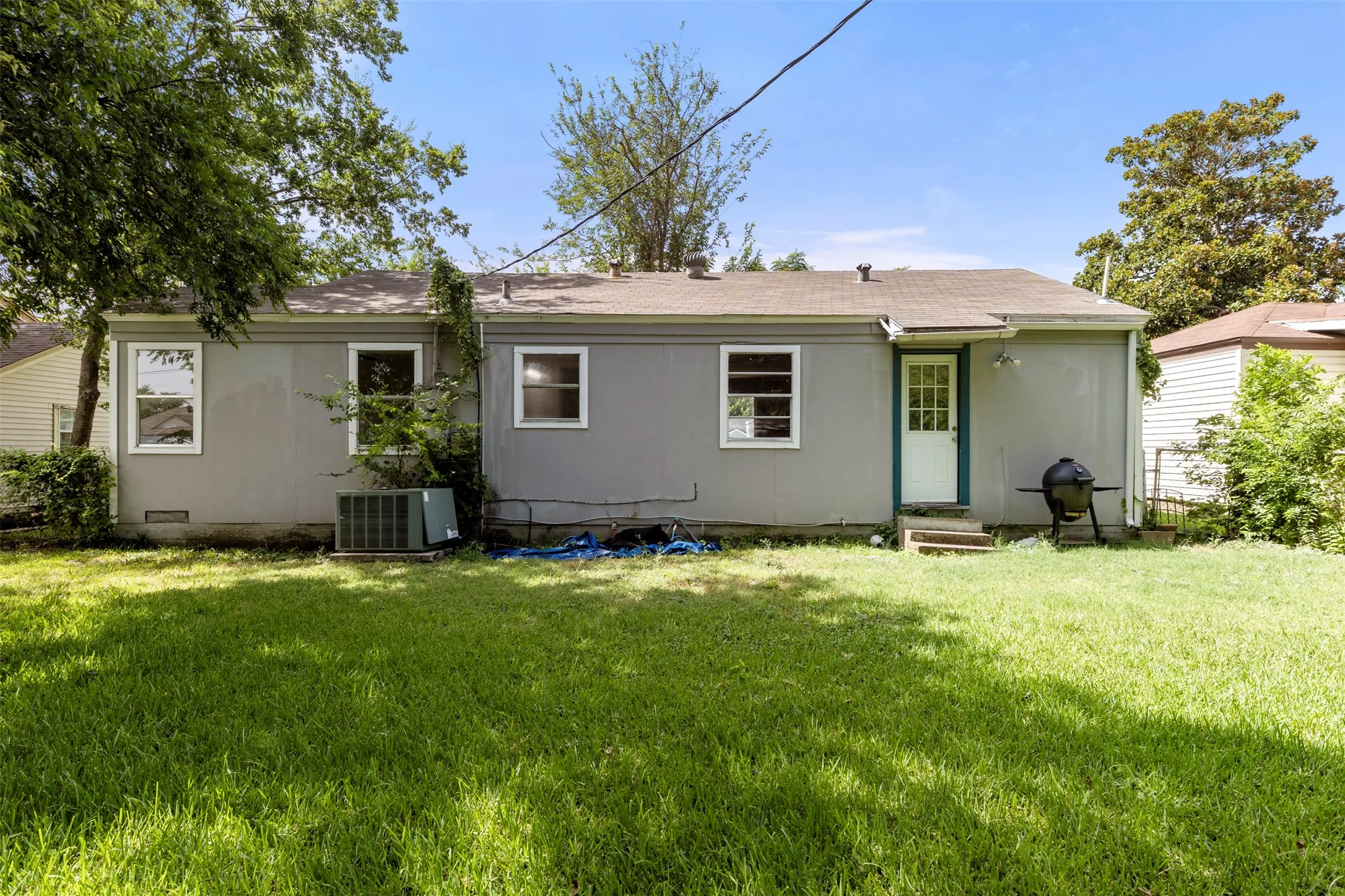 Spacious grassy yard with mature trees providing shade