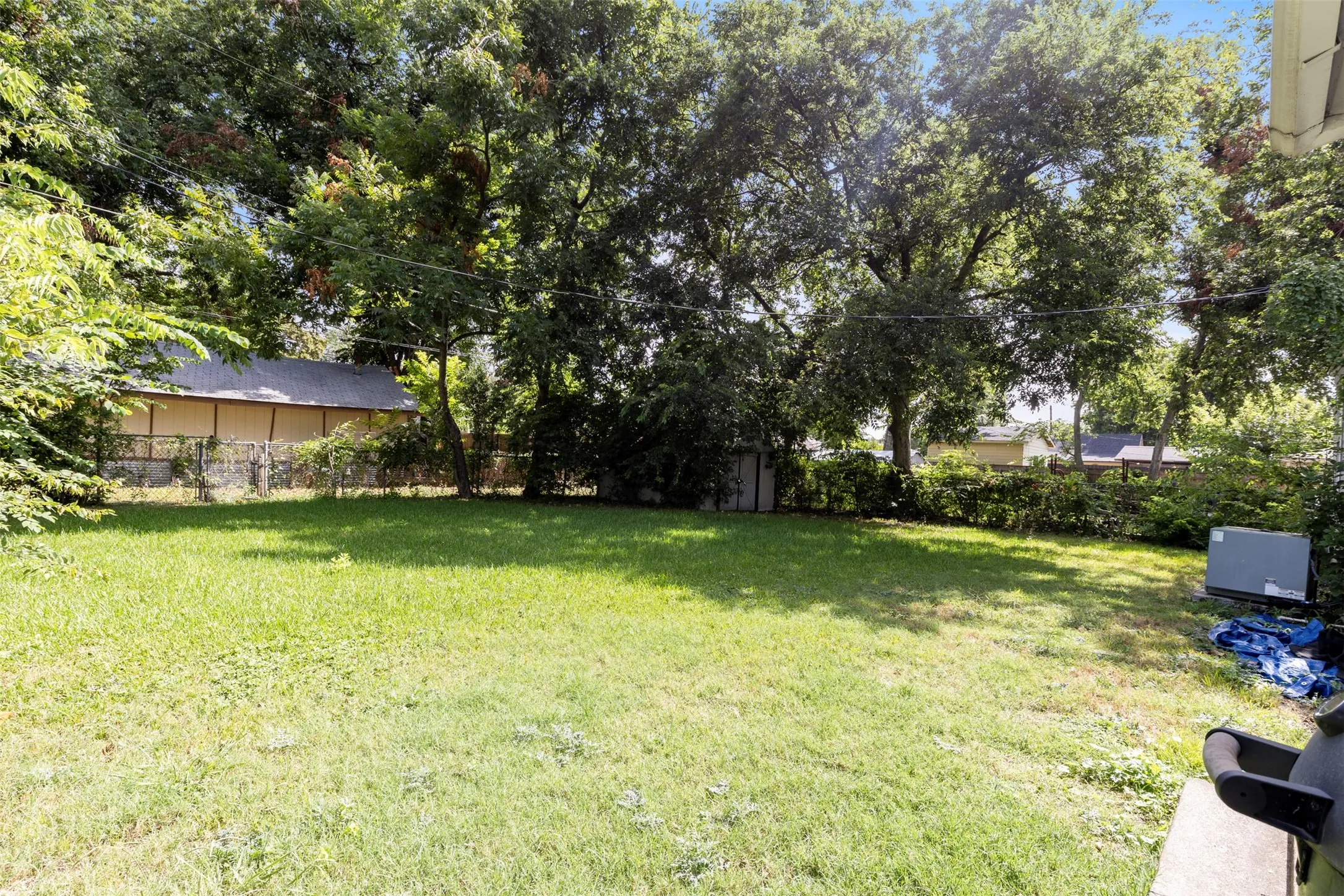 Expansive green lawn with mature trees and a chain-link fence