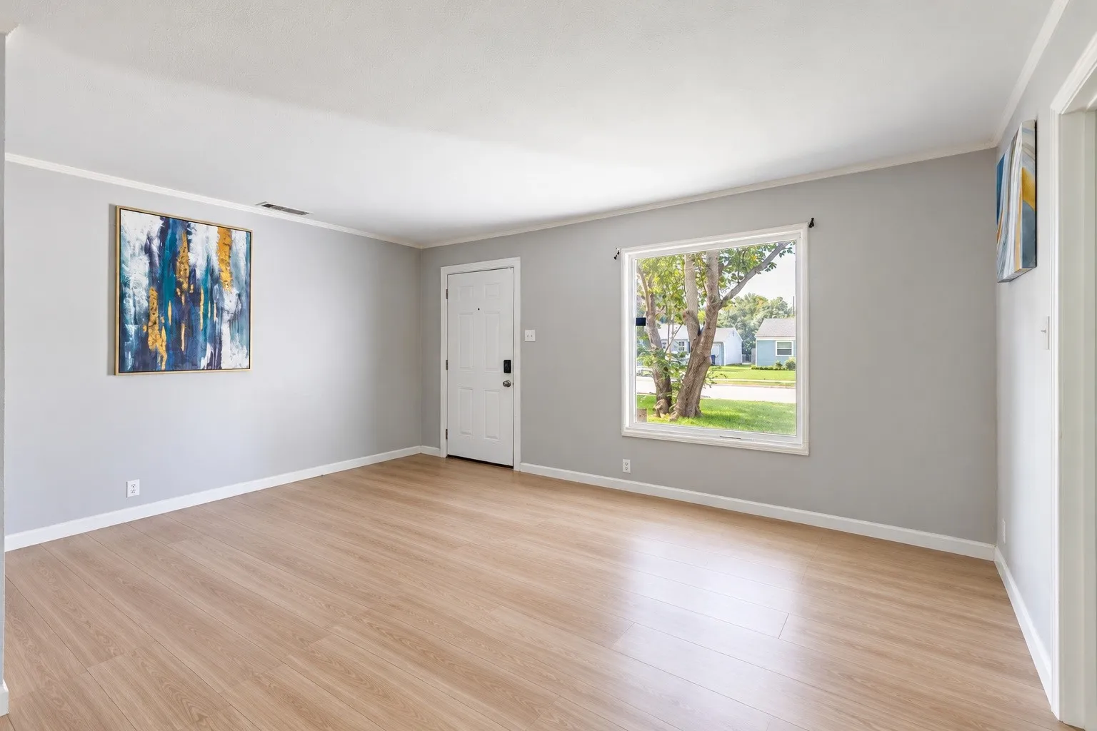 Wood-finish flooring, light gray wall tones, white trim, and a white entry door