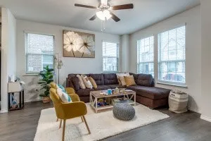 Spacious room featuring multiple large windows, wood-finish flooring, and a ceiling fan with integrated lighting