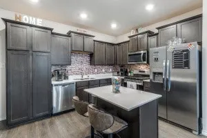 Modern kitchen featuring dark wood-finish cabinetry and a central island with a light-colored countertop