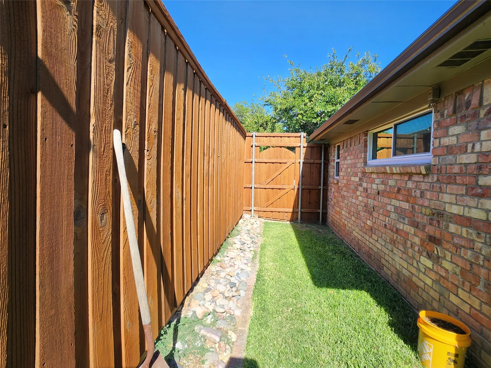 Side yard featuring a red brick exterior, wood privacy fence, and a wooden gate