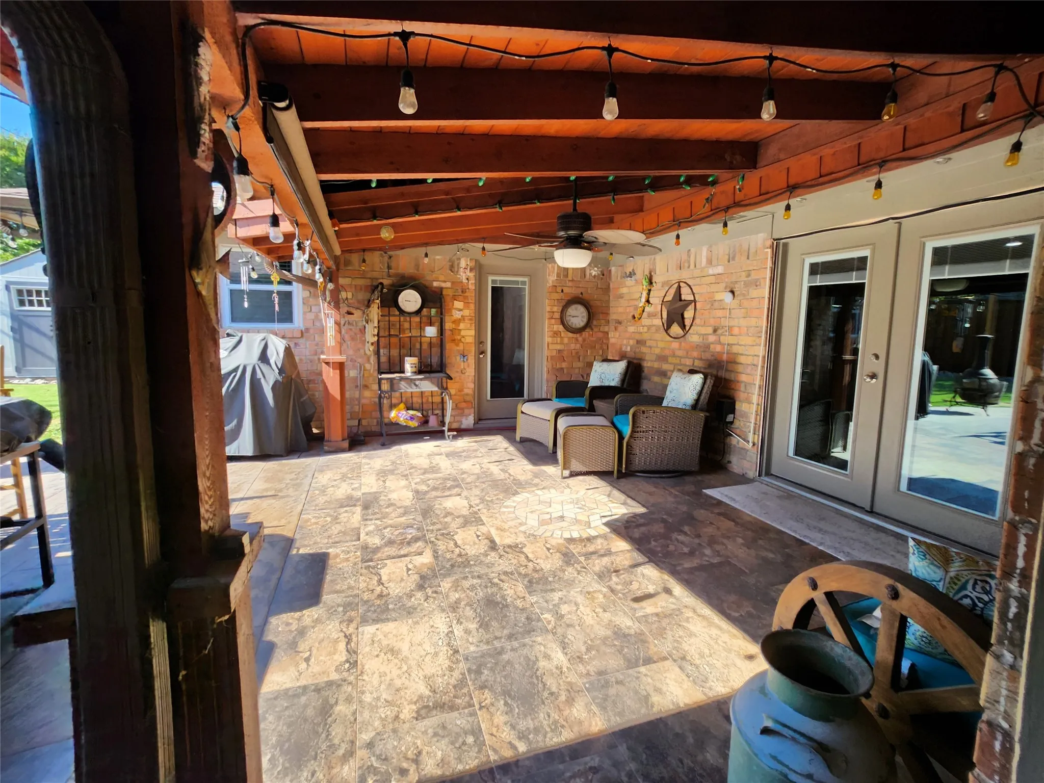 Covered patio featuring a wood beam ceiling, string lighting, and ceiling fan