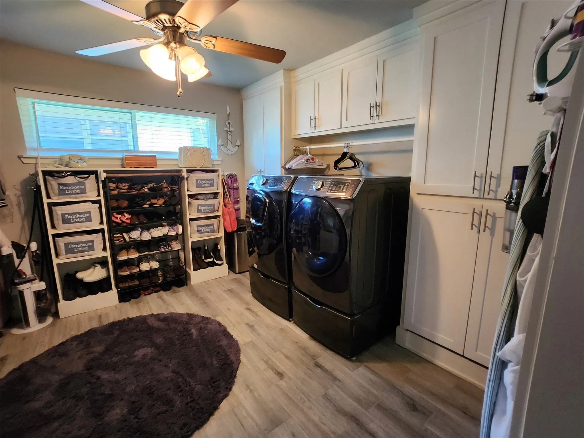 Dedicated laundry area featuring a window, built-in cabinetry, wood-finish flooring, and a ceiling fan with integrated lighting