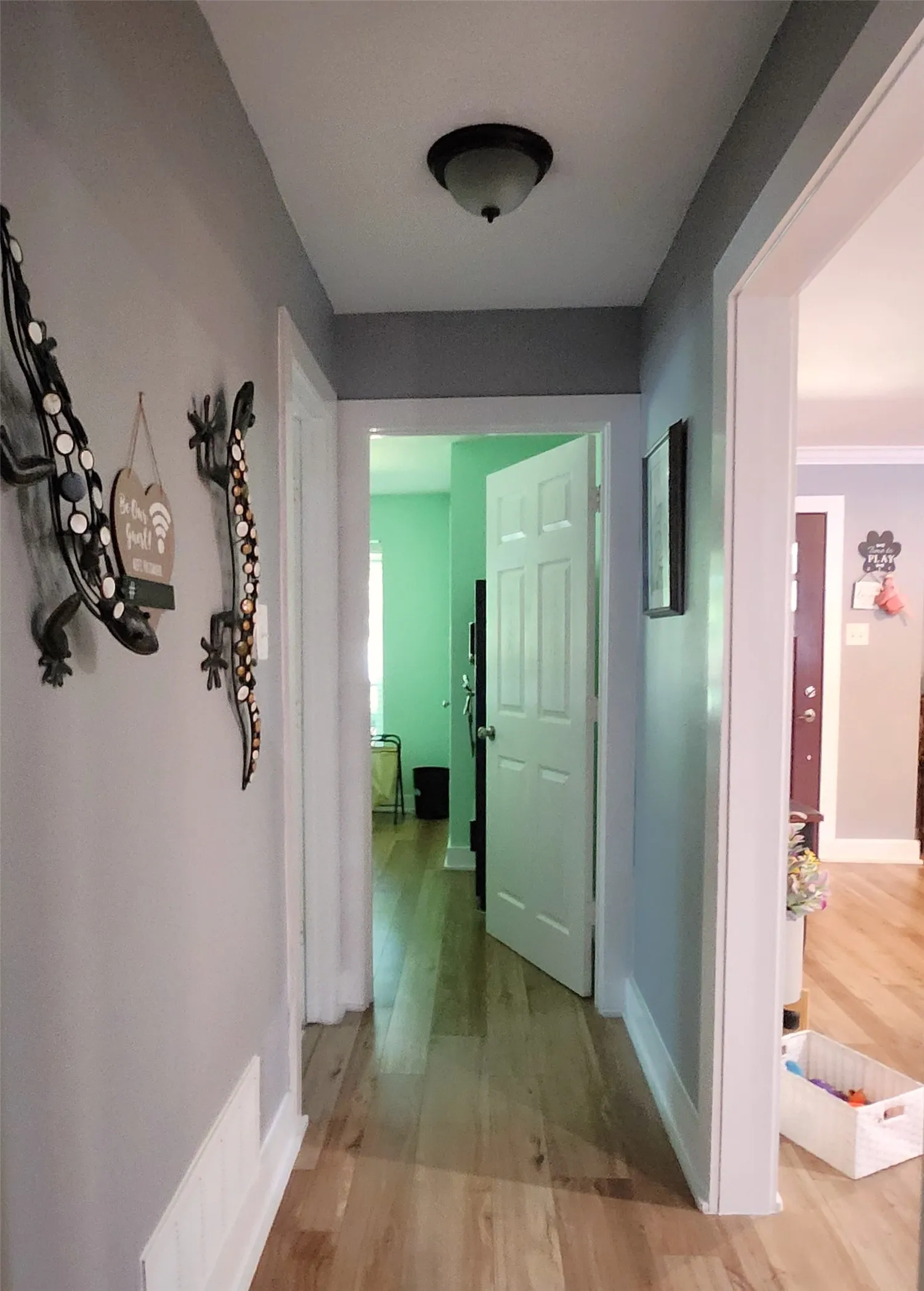 Hallway featuring light wood-finish flooring, white baseboards, and a semi-flush mount ceiling light fixture