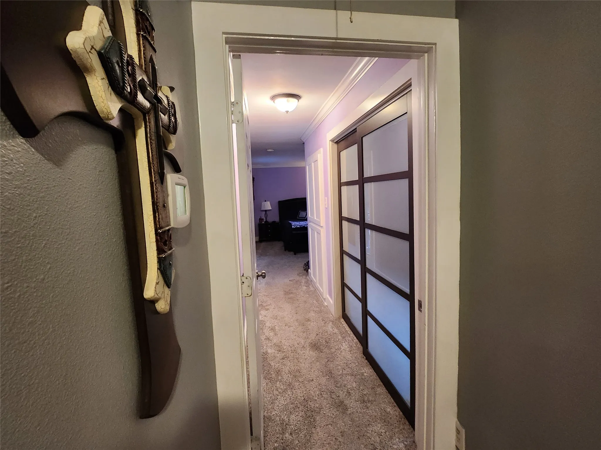 Hallway featuring modern sliding doors with frosted panels, crown molding, and recessed lighting