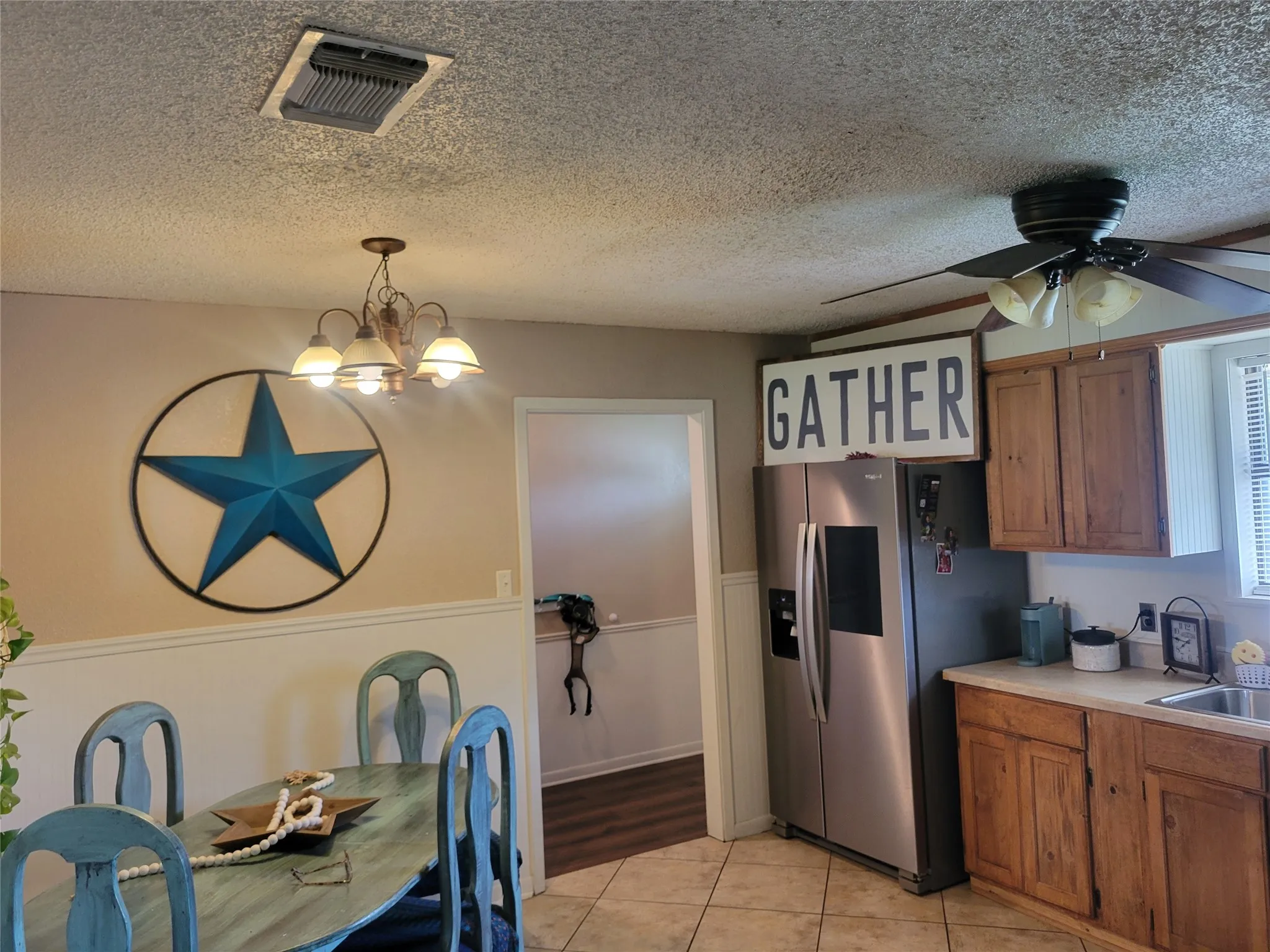 Open-concept living space featuring a dining area with chair rail molding, a chandelier, and an entryway to another room