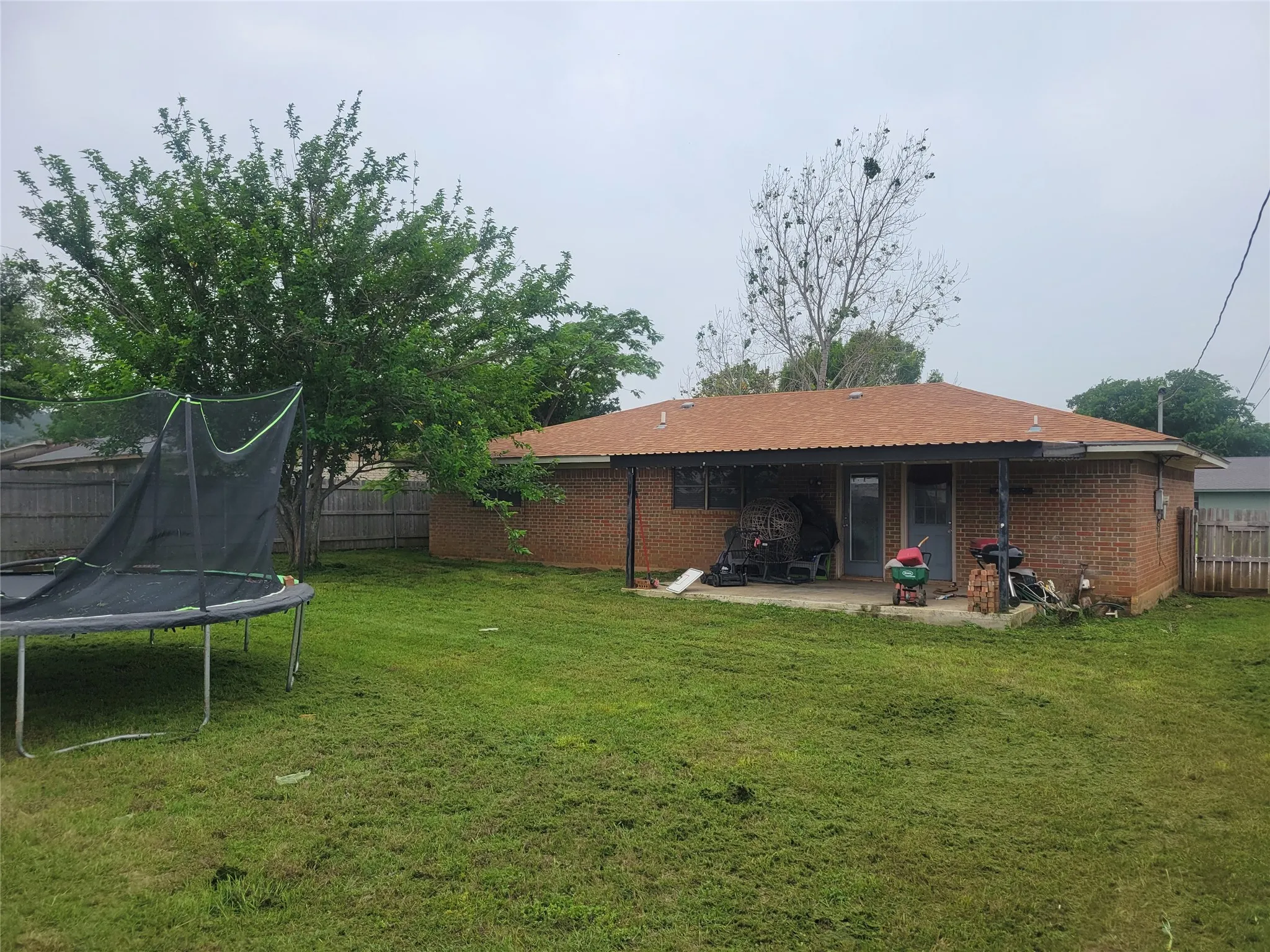 Expansive backyard featuring a manicured lawn, mature trees, and a wooden privacy fence