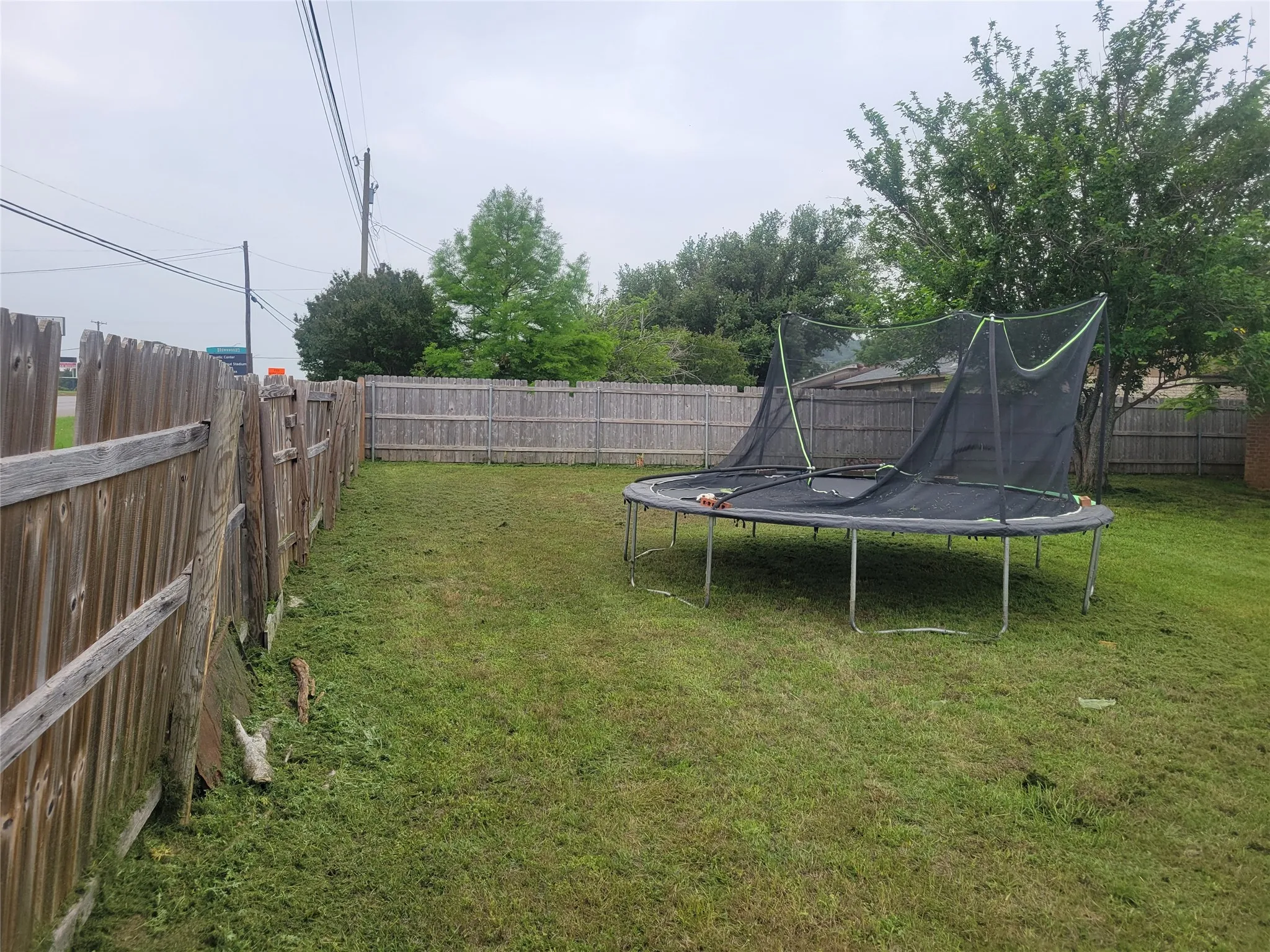 Expansive fenced backyard featuring a grassy lawn and mature trees