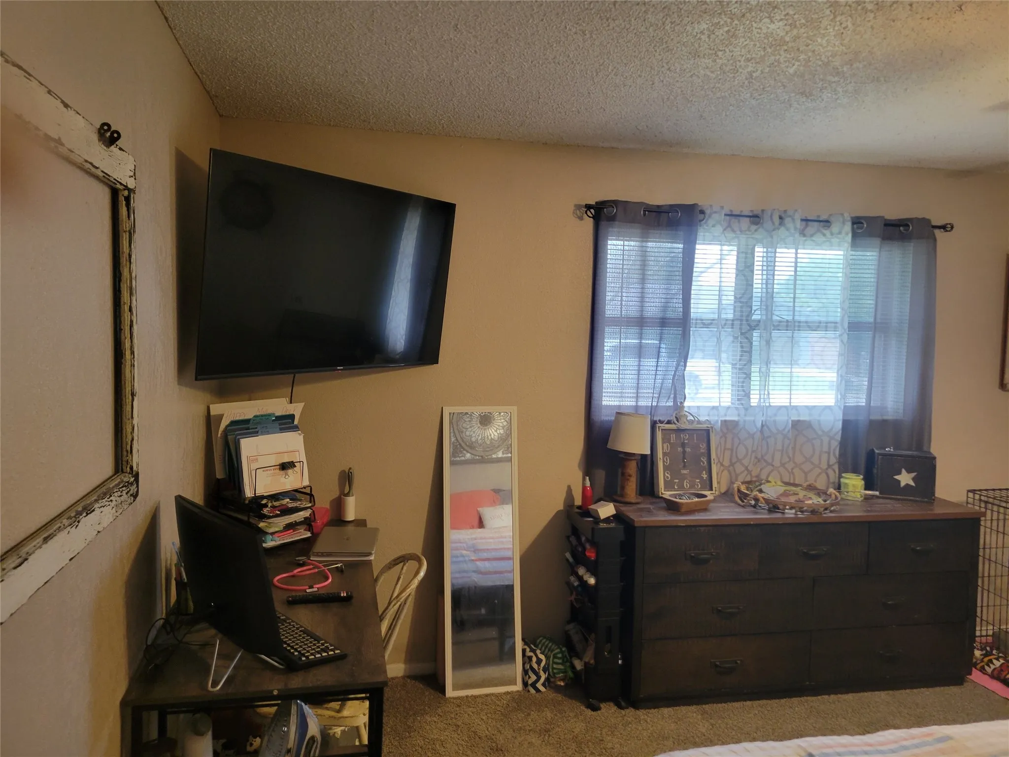 Wall-mounted television with a corner desk featuring a wood-finish top and metal frame