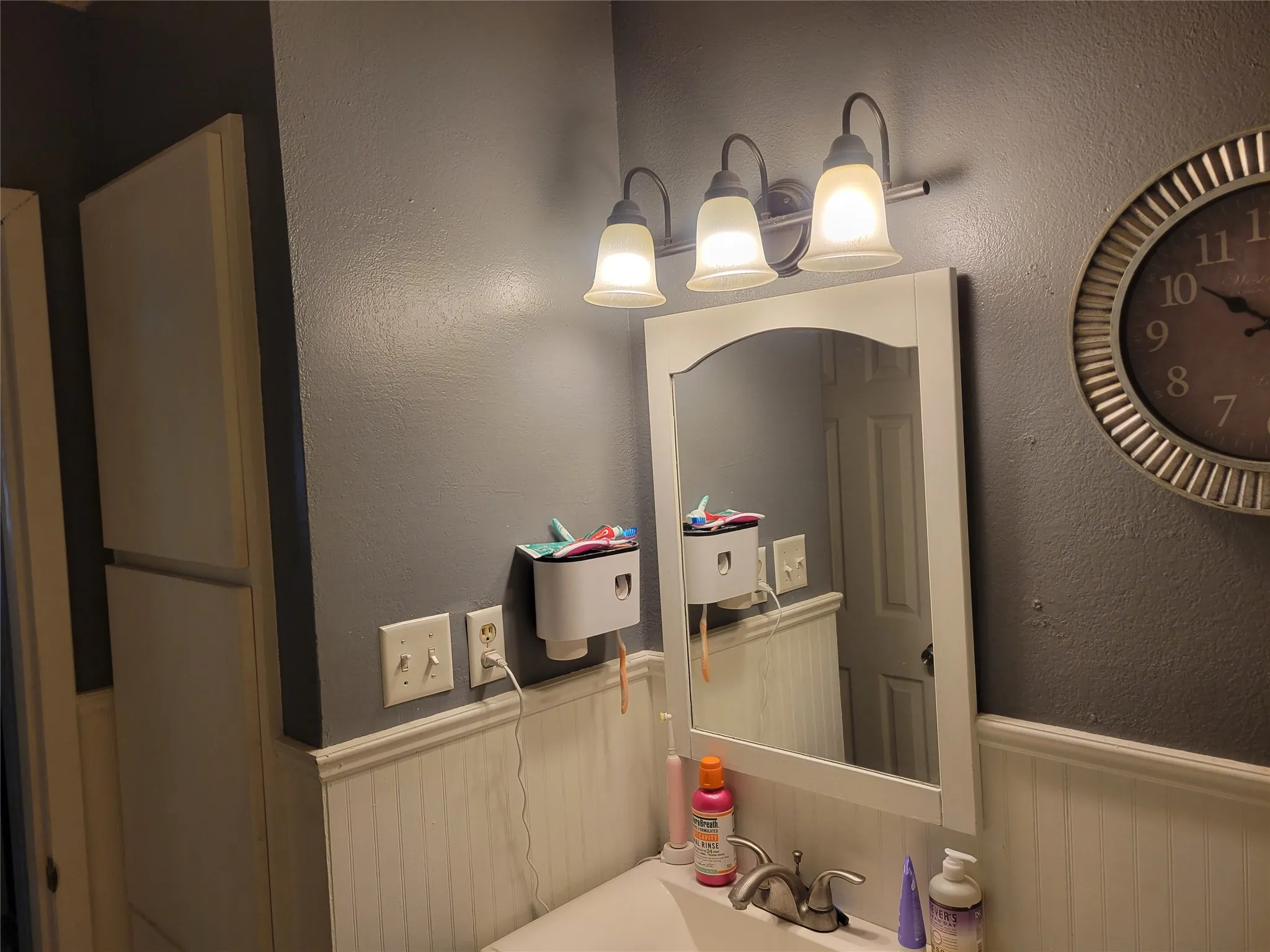 Vanity area featuring a white framed mirror, three-light fixture, and beadboard wainscoting