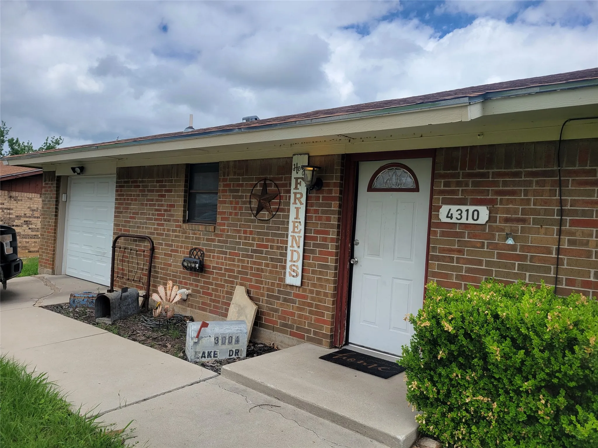 Brick exterior with an attached garage and a white entry door featuring an arched window