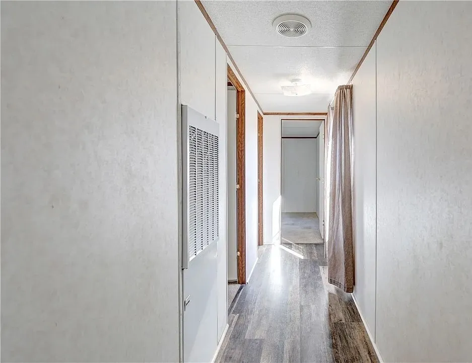 Hallway featuring wood-finish flooring, white panel walls, and recessed ceiling lighting