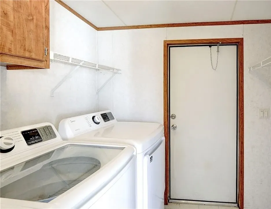 Dedicated utility area featuring wood-finish cabinetry, white wall shelving, and a white entry door with a wood-finish frame