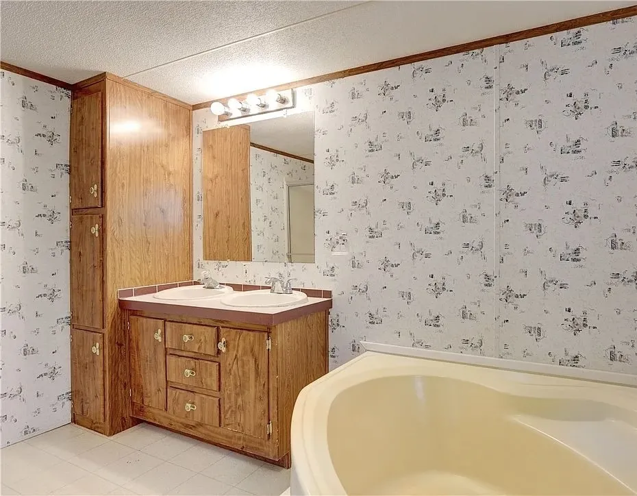 Bathroom featuring a double vanity with wood-finish cabinetry, dual undermount sinks, and a wall-mounted mirror