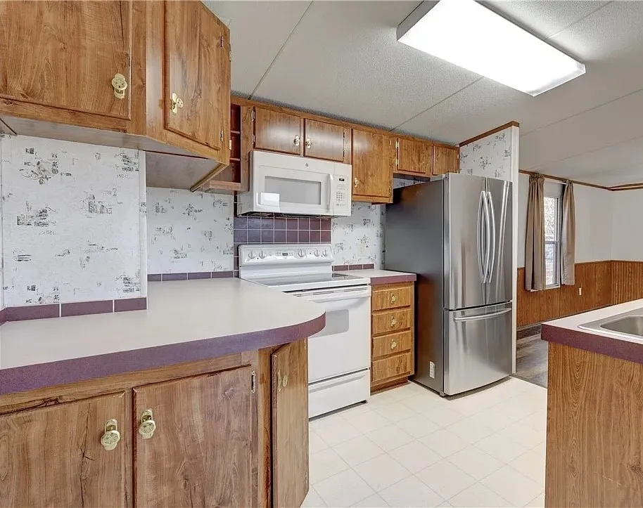 Kitchen featuring wood-finish cabinetry, white countertops, and a tile backsplash