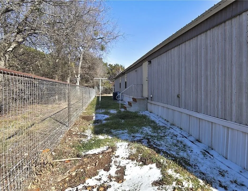 Chain link fence with a top rail, bordering a perimeter of trees