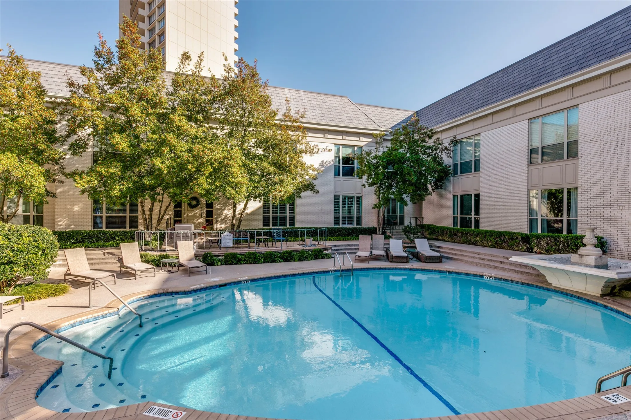 Beautiful swimming pool, fountain, and patio furniture.