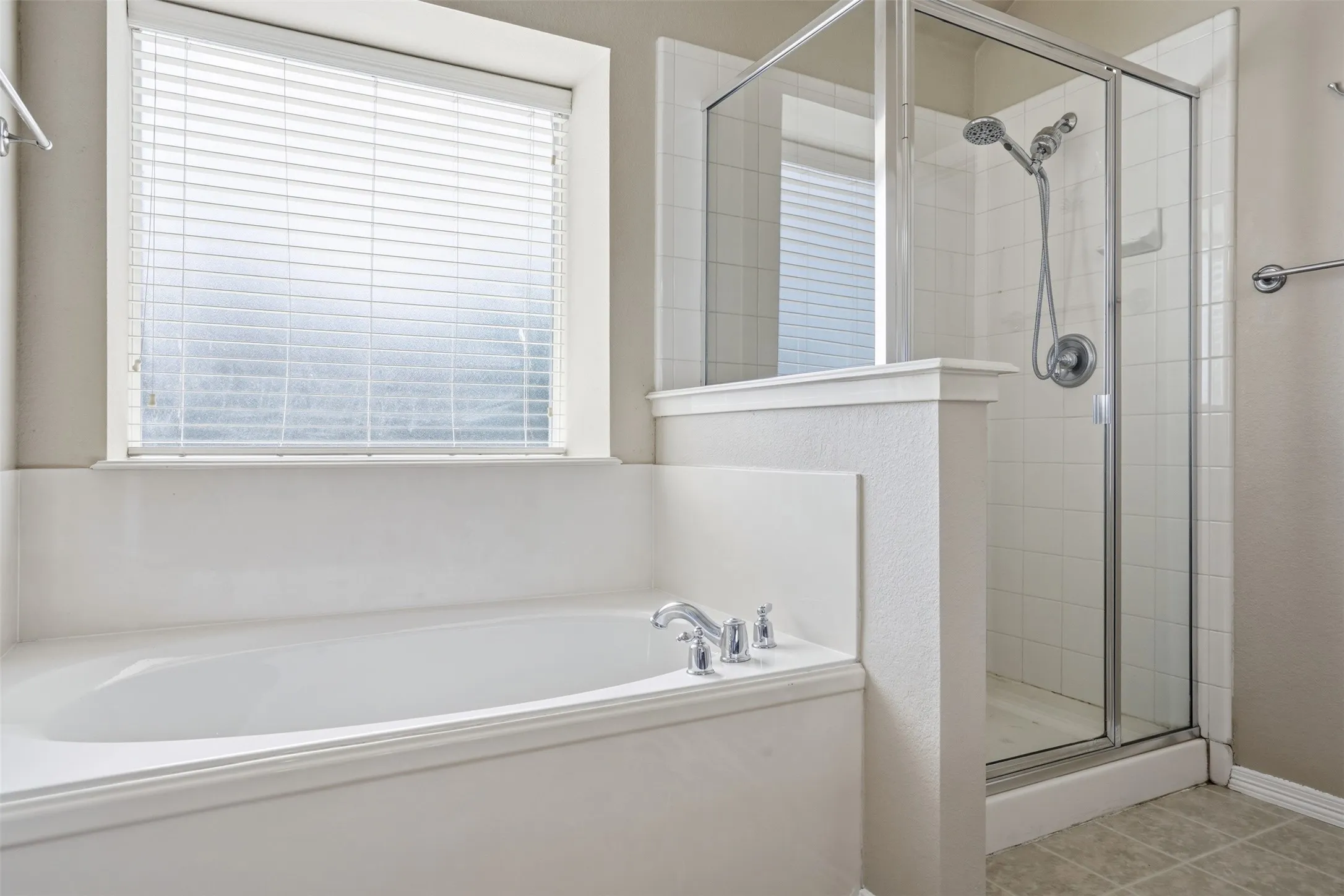 Primary bathroom featuring a soaking tub, separate glass-enclosed shower, and a large window that bathes the room with natural light.