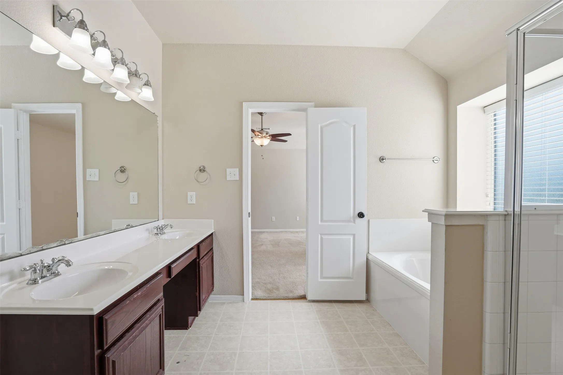 Primary bathroom featuring a soaking tub, separate glass-enclosed shower, and a large window that bathes the room with natural light.