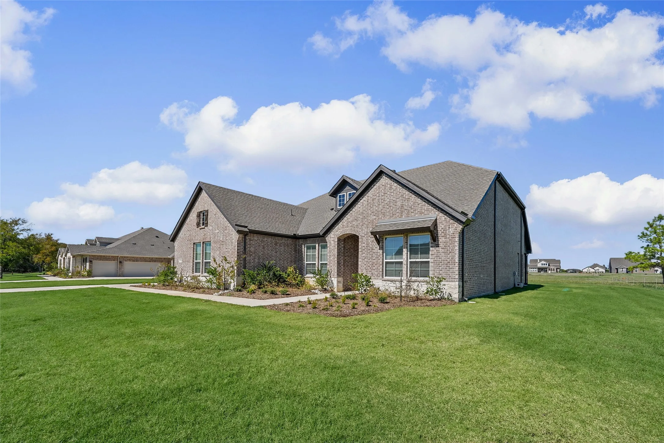 Brick exterior with architectural shingles, arched entryway, and multiple gables