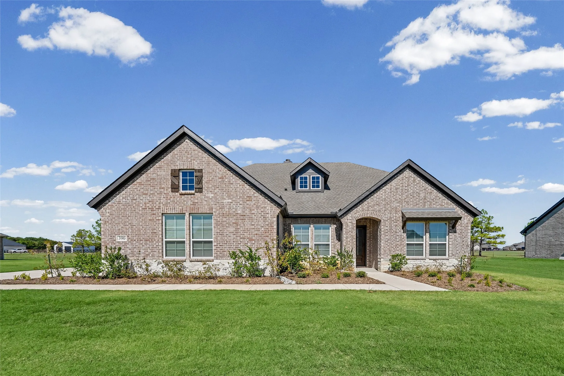 Brick exterior with stone accents, gabled roofline, dormer window, covered entry, and awning window