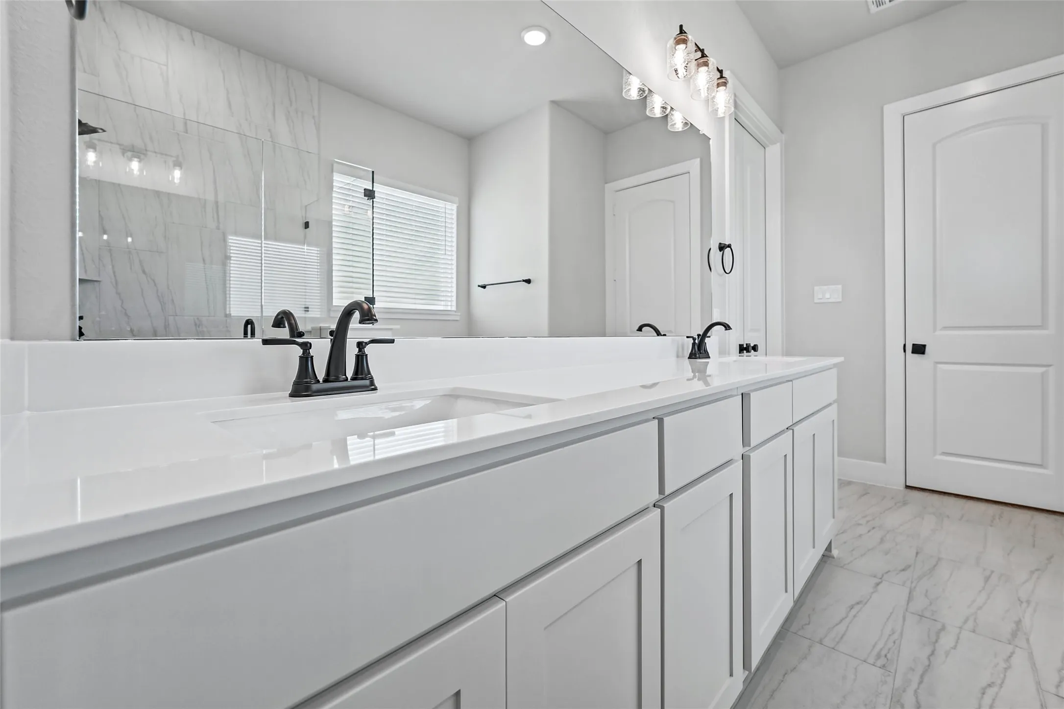 Dual vanity with white cabinetry, white countertops, matte black fixtures, and a large mirror