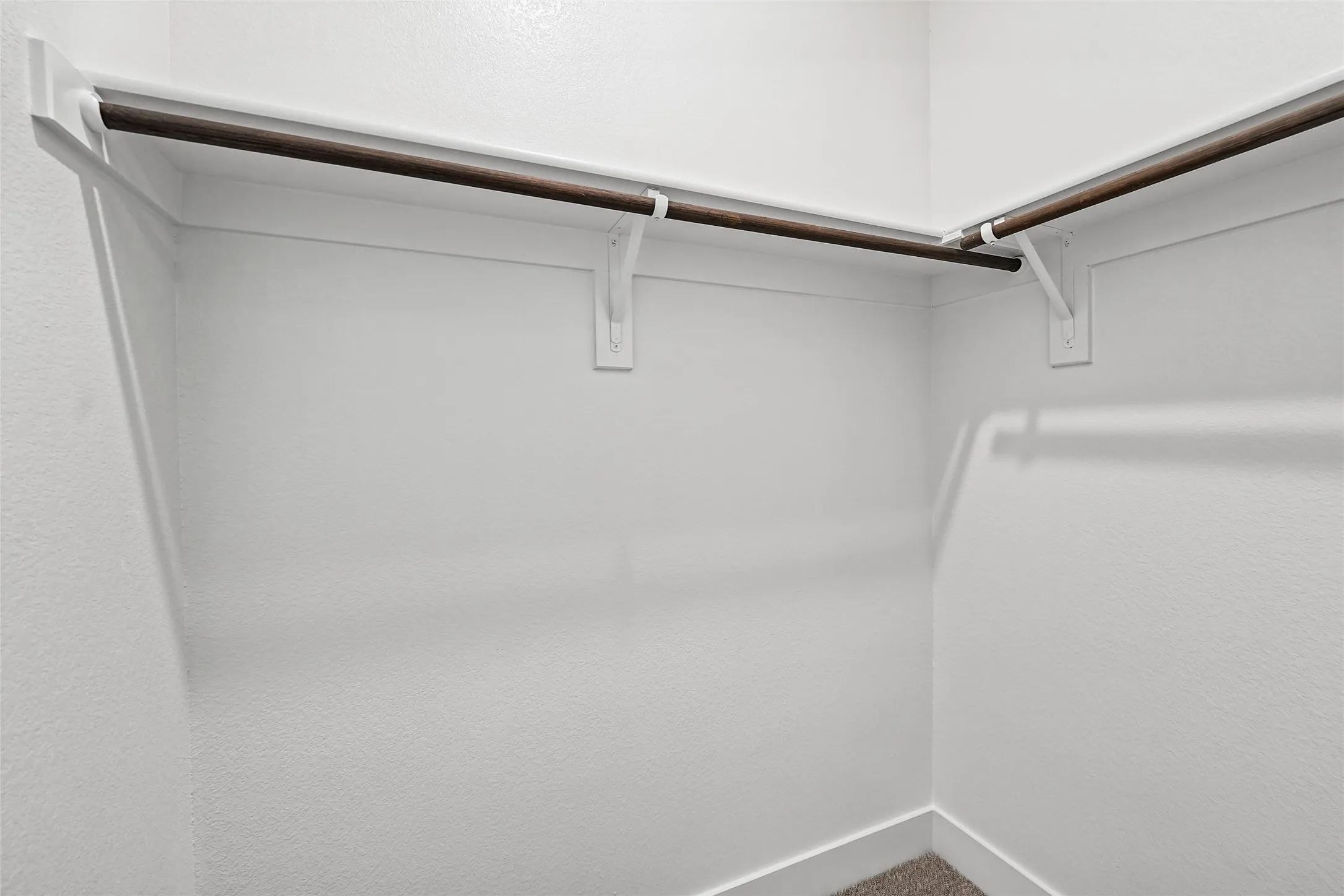 Corner walk-in closet with wall-mounted shelving and clothing rods